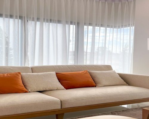 Living room with large windows and sheer curtains diffusing strong sunlight
